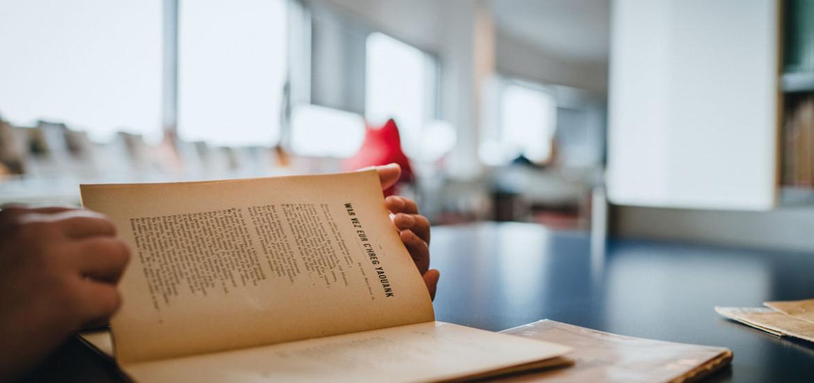 Mains qui tiennnet un livre ancien dans une bibliothèque