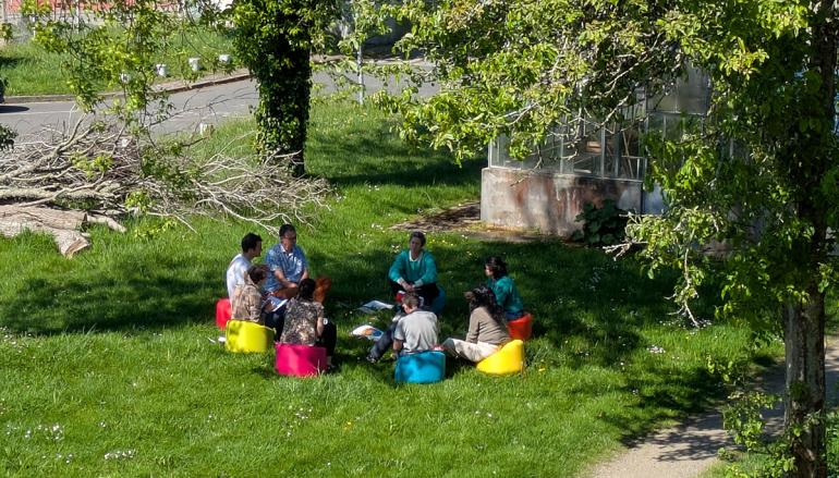 des étudiants et personnels sur des poufs dans l'herbe pendant un cours en plein air